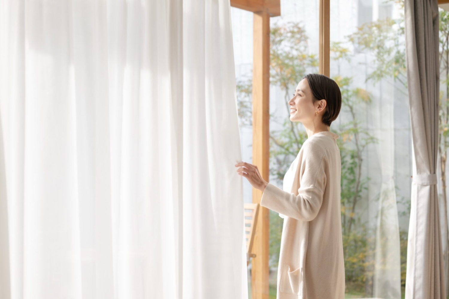 家のカーテンを閉める女性