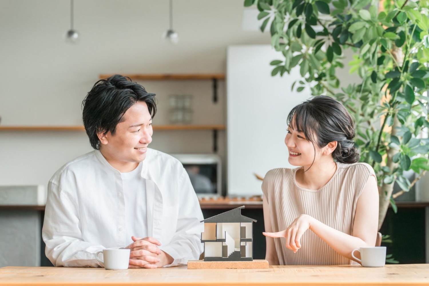住宅模型を見てマイホームの間取りを検討する若い夫婦