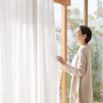 家のカーテンを閉める女性
